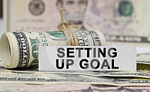 On the table are bills, a bundle of dollars and a sign on which it is written - SETTING UP GOAL