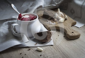 On the table a blue napkin with ornament pattern and soup tureen with red beet soup on the sun bread garlic sour cream