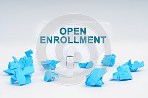 On the table are blue pieces of paper and paper with the inscription - OPEN ENROLLMENT