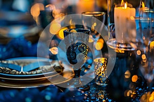 A table with a blue tablecloth and a black wine glass with a gold napkin