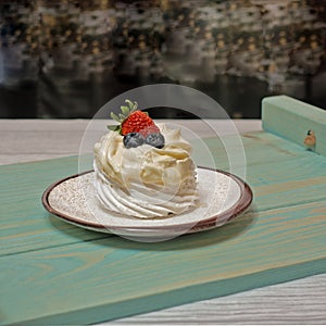 On the table, on a blue wooden tray, is a meringue.