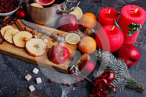 On the table is a board with apples, next to several candles, a pan with sangria and a plate with cranberries. Top view.