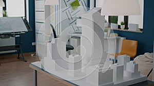 Table with building model and maquette presentation in empty architectural space