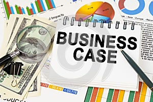 On the table are business charts, dollars and a notepad with the inscription - Business Case