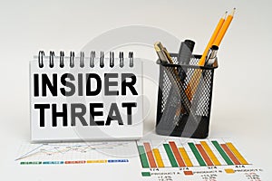 On the table are business charts, office supplies and a notepad with the inscription - insider threat