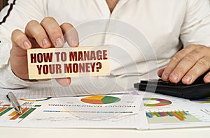 On the table of business graphics in the hands of a man is a bar with the inscription - How to manage your money