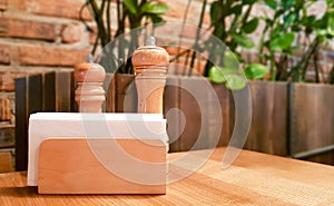 A table in a cafe or restaurant. White napkins in a wooden napkin holder, spices salt and pepper on a wooden table, panoramic view