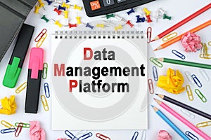 On the table is a calculator, diary, markers, pencils and a notebook with the inscription - Data Management Platform