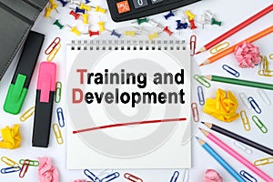 On the table is a calculator, diary, markers, pencils and a notebook with the inscription - Training and Development