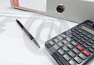 Table with calculator,file binder and pen.