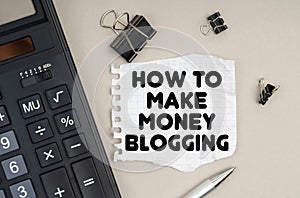 On the table is a calculator, a pen and paper with the inscription - How To Make Money Blogging