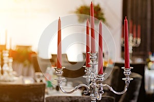 On the table is a candlestick made of metal with red candles. Decoration for holiday or celebration. selective focus.