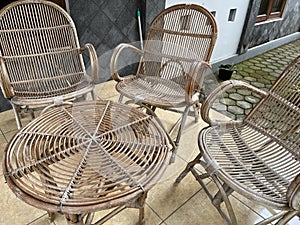 Table and chair made from rattan outside a house.