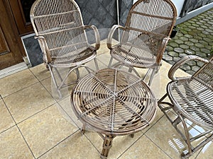 Table and chair made from rattan outside a house.