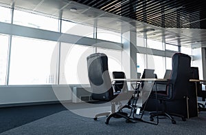 Table and chairs in the interior of a modern office with large panoramic windows against the backdrop of city