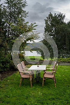 Table and chairs on lawn by lake on cold autumn day