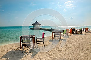 Table and chairs at restaurant at the background of water bungalows, Maldives island