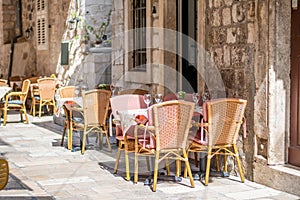 Table and chairs at the restaurant in narrow street are prepared for guests and tourist. Old city of Dubrovnik, Croatia