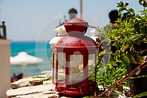 Red small lantern as decoration at a seacoast restaurant.able in cozy outdoor cafe with a small lantern and plant