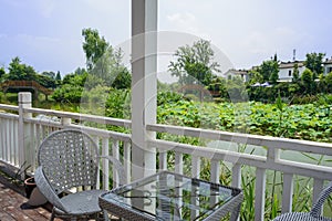 Table and chairs in veranda of lakeside wooden cabin at sunny summer nooon