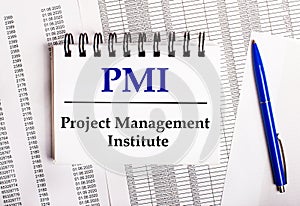 On the table are charts and reports, on which lie a blue pen and a notebook with the word PMI Project Management Institute