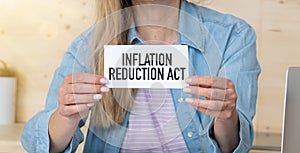 On the table charts, woman and paper card with the INFLATION REDUCTION ACT text photo