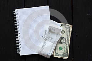 on the table a check from the supermarket and dollars were brought in notebooks, a paper receipt with purchases, money