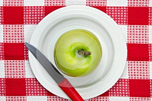 Table cloth with plate and green apple on it