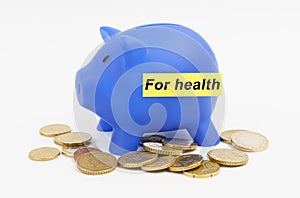 On the table are coins and a blue piggy bank with the inscription - For health