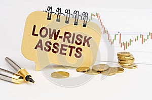 On the table are coins, a pen, a graph and a sign with the inscription - Low-risk assets