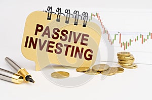 On the table are coins, a pen, a graph and a sign with the inscription - Passive Investing