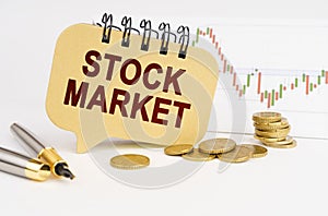 On the table are coins, a pen, a graph and a sign with the inscription - STOCK MARKET