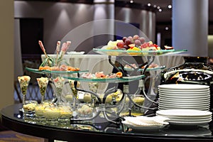 Table with cold snacks and fruits on stand