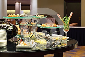 Table with cold snacks on stand and tableware