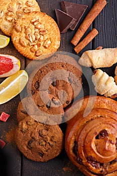 On the table is a composition of various pastries, cinnamon, chocolate and citrus. View from above. Inside.