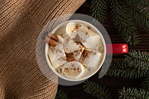 On a table decorated with Christmas decor, there is a cup of hot chocolate