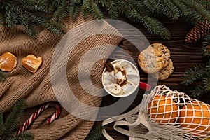 On a table decorated with Christmas decor, there is a cup of hot chocolate and holiday cookies