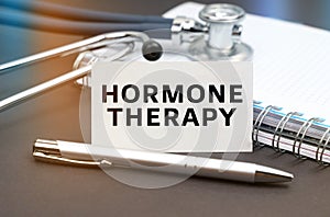 On the table is a diary, a stethoscope and a business card with the inscription - HORMONE THERAPY