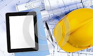 Digital tablet with pen and yellow helemet on