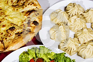 A table with dishes of khinkali and khachapuri. Close-up photo. The concept of traditional Georgian national cuisine.