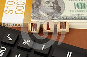 On the table are dollars, a calculator and cubes with the inscription - MLM