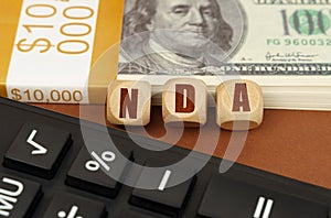 On the table are dollars, a calculator and cubes with the inscription - NDA