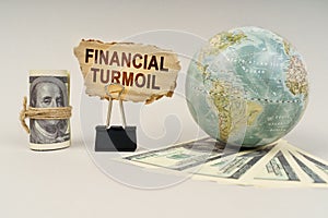 On the table are dollars, a globe and there is a sign with the inscription - financial turmoil