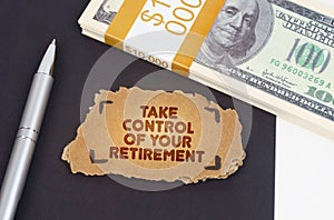 On the table are dollars, a pen and a cardboard sign with the inscription - take control of your retirement