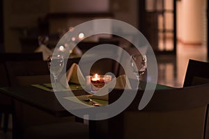 A table at a fancy restaurant candle light romantic dinner setting dim lighting