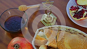 On the table are festive treats for Rosh Hashanah challah, honey, and pomegranate