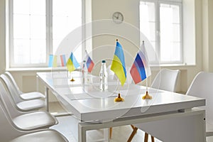 Table with flags of Ukraine and Russia at negotiation on stopping war and restoring peace