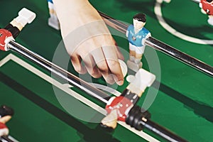 Table football in the entertainment center. Close-up image of a girl throwing a toy ball into a game of football