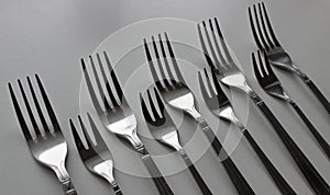 The table forks and cake forks are laid out in order one after the other on white