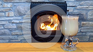 On the table in front of the fireplace is glasses of cocktail, a concept of a romantic evening